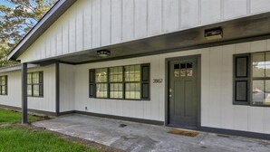 A single-story building with a white exterior, numbered 2862, featuring a front door, windows, and a small porch area. - Updated 4 bedroom home in Oragnefield (Orange)