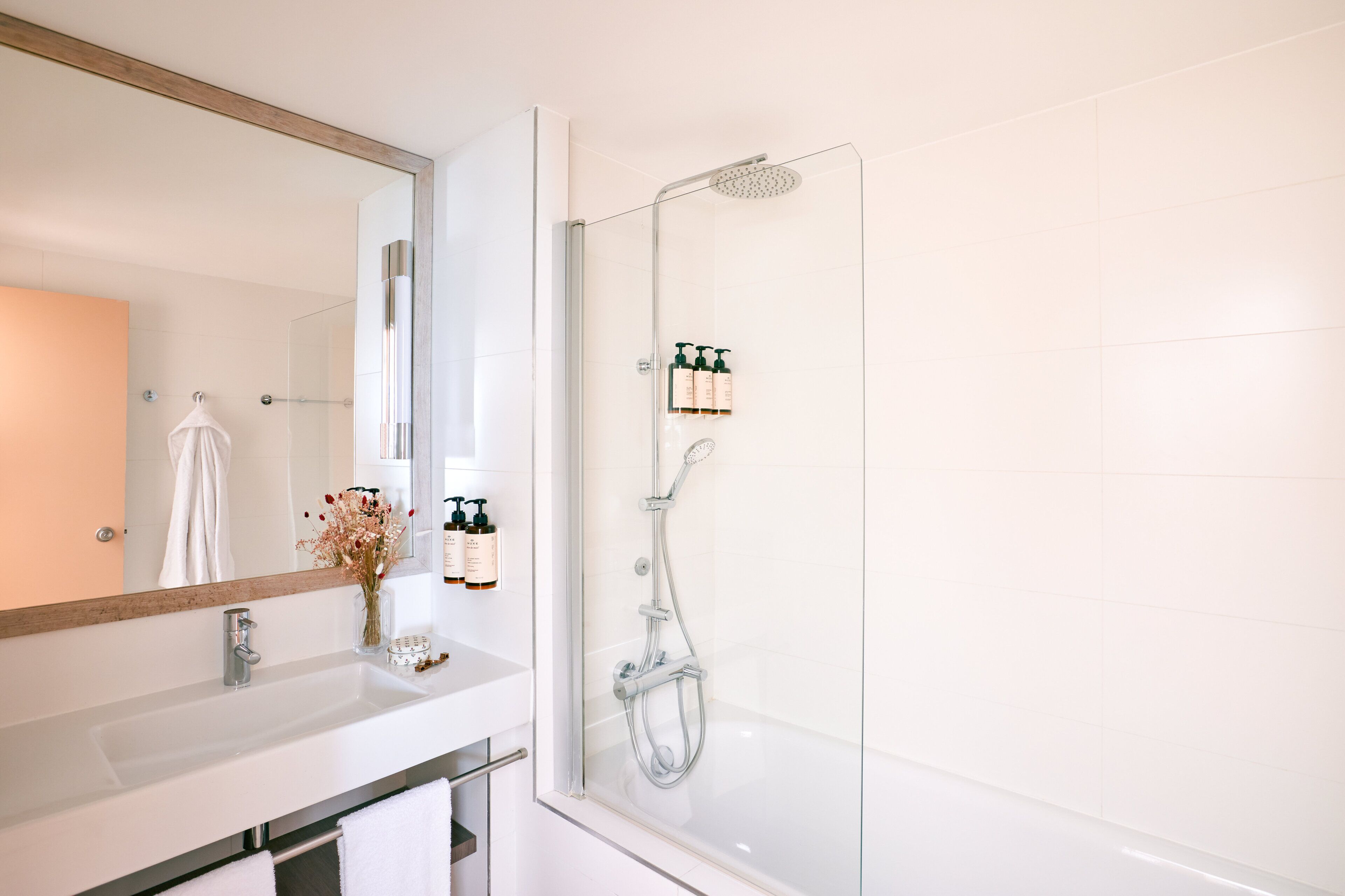 A modern bathroom with a glass-enclosed shower, a white sink, and a large mirror.