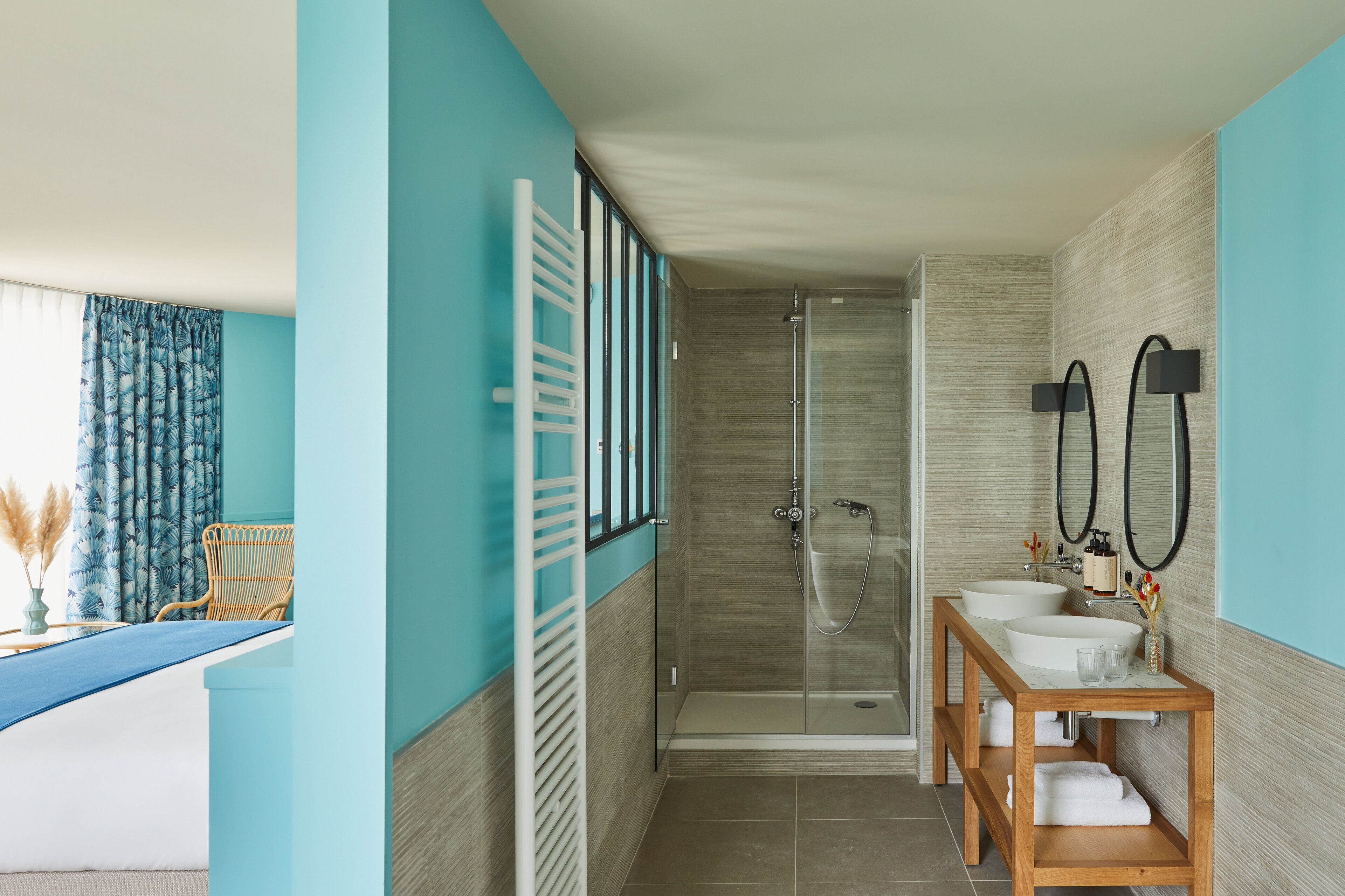 A bathroom with a glass shower enclosure, two sinks, and a wooden vanity.