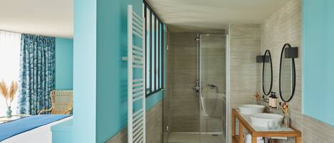 A bathroom with a glass shower enclosure, two sinks, and a wooden vanity.