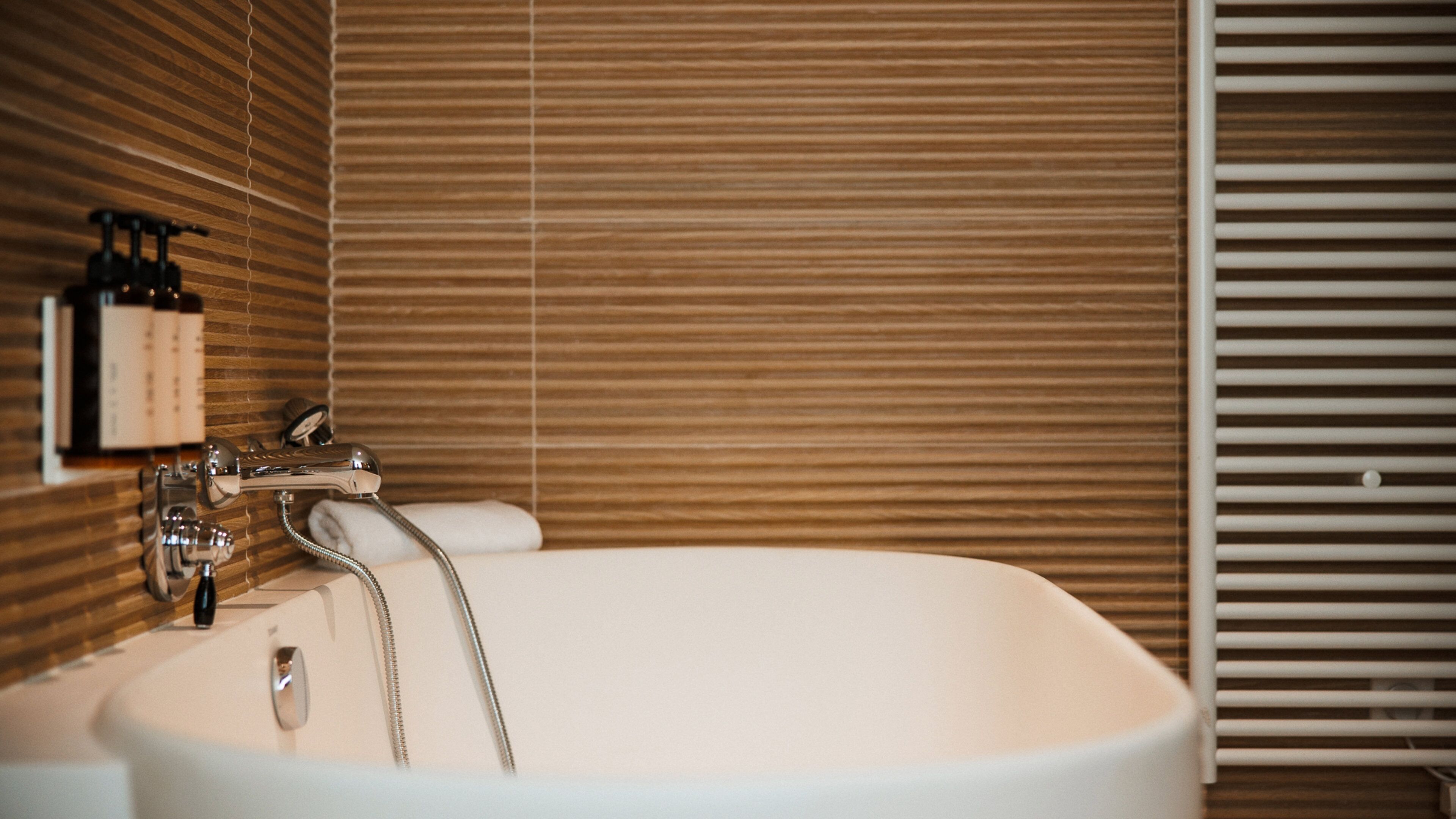 Une salle de bain avec une baignoire sur pieds, un porte-serviettes et un distributeur de savon fixé au mur.