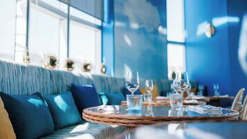 A dining area with a table set for two, featuring a woven placemat, a glass of water, and a wine glass.