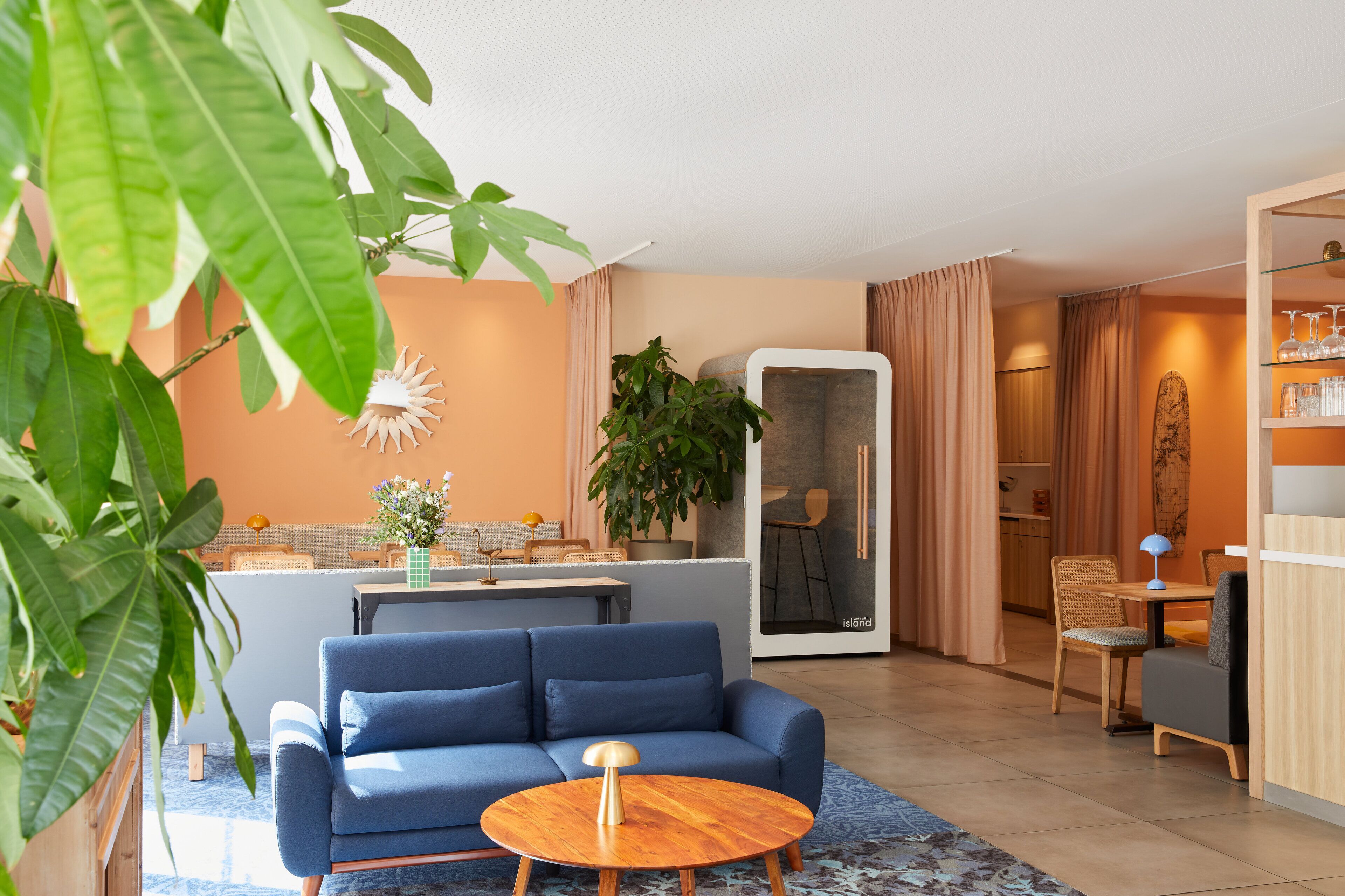 A modern living room with a blue sofa, a round wooden coffee table, and a large potted plant.
