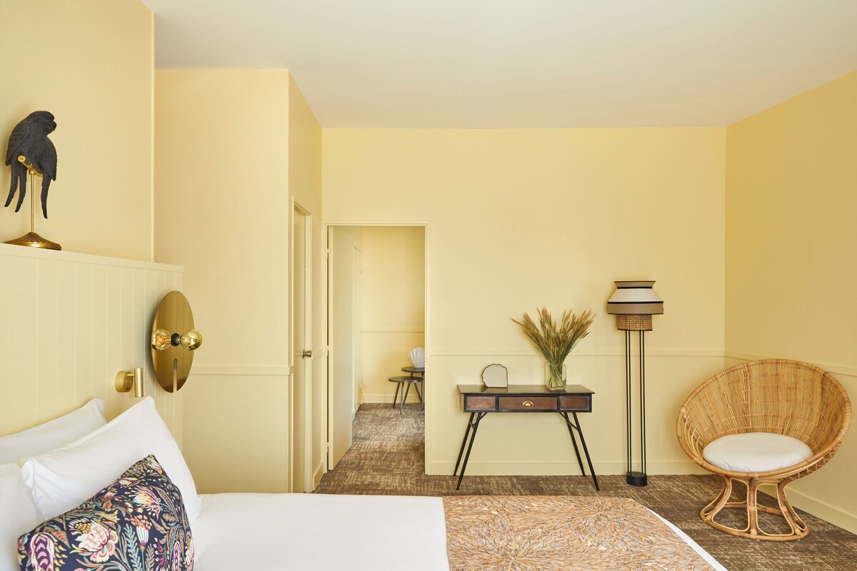 Een hotelkamer met een bed, een bureau, een stoel en een lamp.