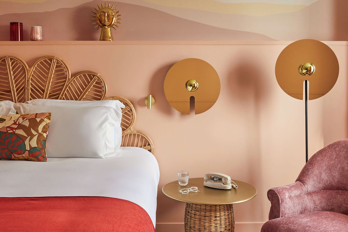 Ein Hotelzimmer mit einem Bett, einem runden Tisch, einem Sessel, einer Wandlampe und einer Wanddekoration.