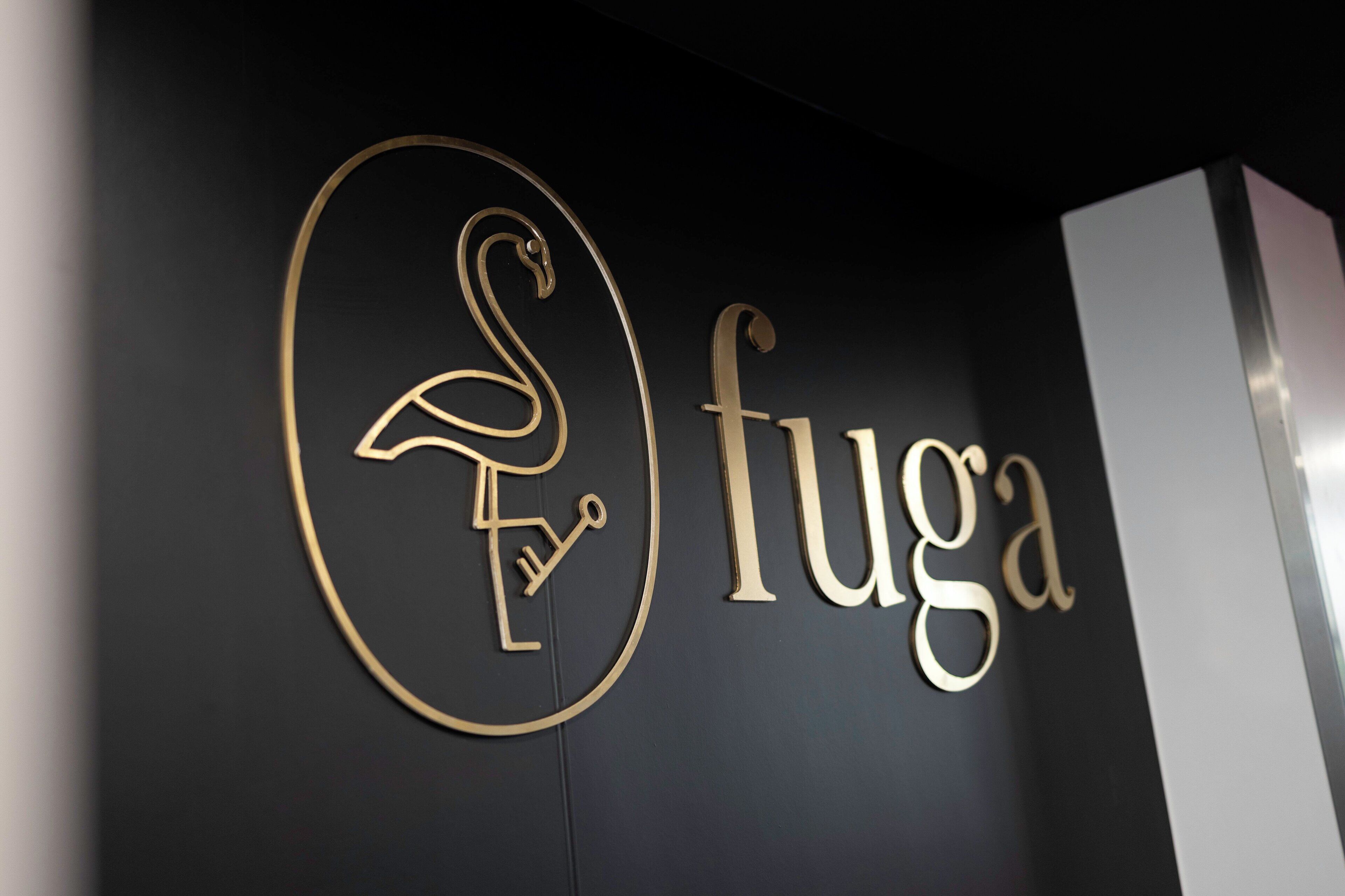Un mur orné d’un logo représentant un flamant stylisé et du mot « fuga ».