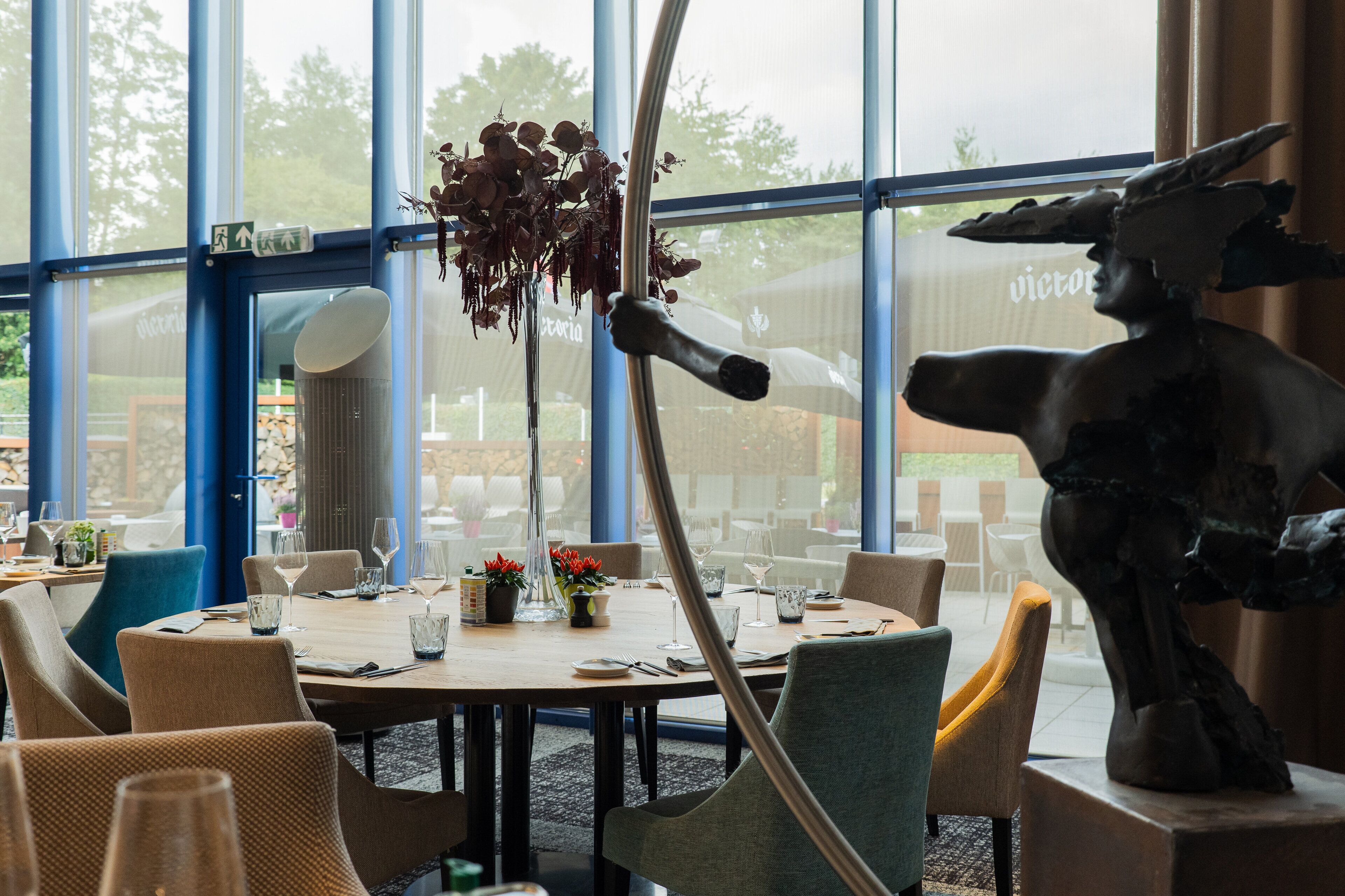 Un restaurant avec des tables rondes, des chaises et une grande fenêtre donnant sur un beau paysage.