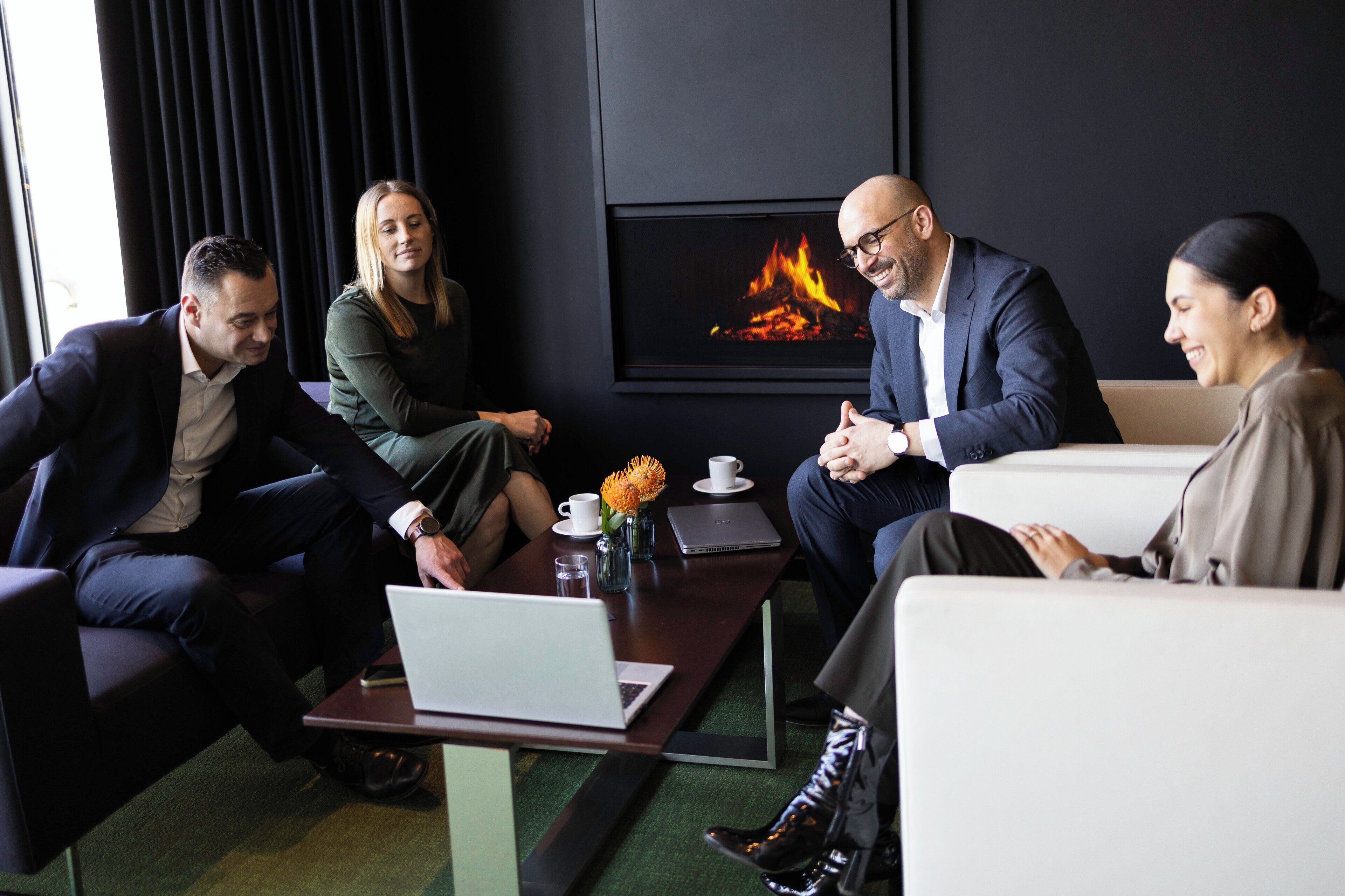Une salle de conférence avec un paravent près d’une cheminée, un ordinateur portable et une tasse de café sur la table.