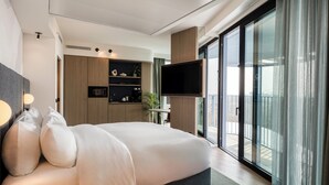 Un dormitorio moderno con una cama grande, un televisor de pantalla plana y un ventanal corredero que da a un balcón.