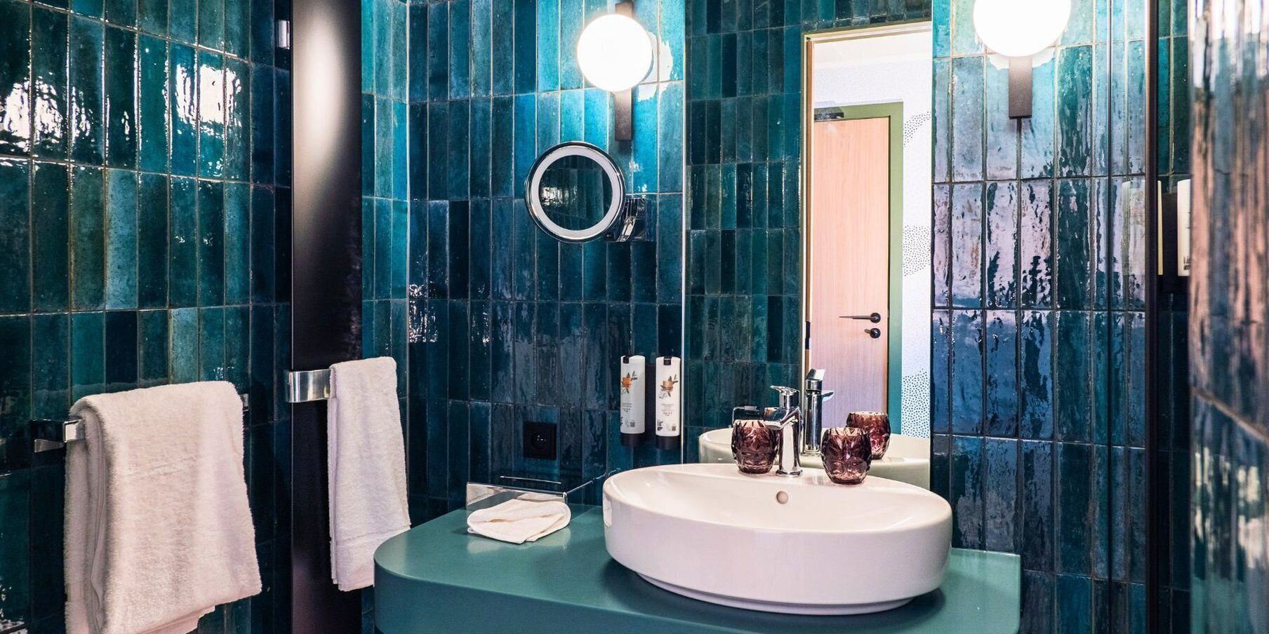 A bathroom with a round sink, a mirror, and two towels on towel racks.