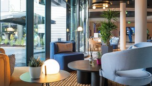 Un vestíbulo moderno con zonas de estar, ventanas amplias y plantas de interior.