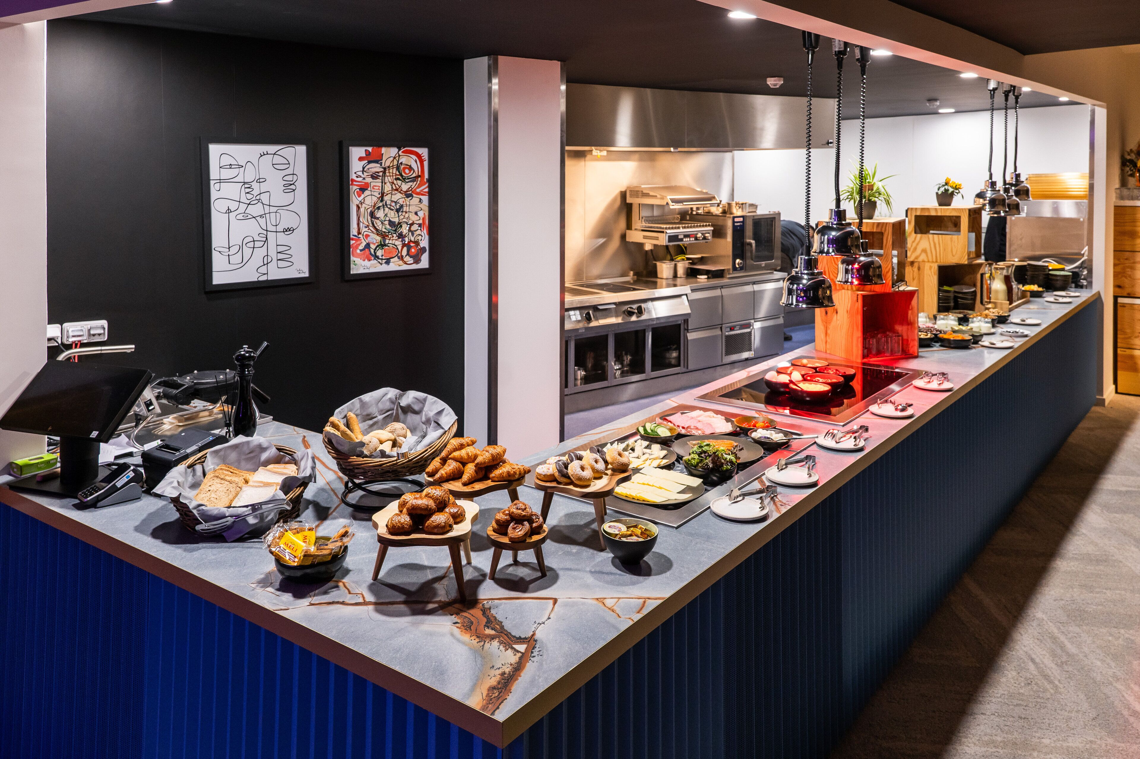 A buffet with various food items and a kitchen area in the background.