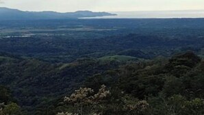 Ein weiter Panoramablick auf eine gebirgige Landschaft mit einem Fluss und weit entfernten Landformen.