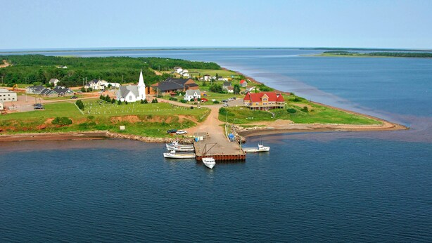 En kuststad med en kyrka, bostadshus och en brygga med båtar.