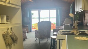 Ett kök med utsikt över en sjö, en matplats med en stol och en öppen spis.