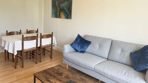 Una sala de estar con un sofá, una mesa de comedor con sillas y un cuadro en la pared.