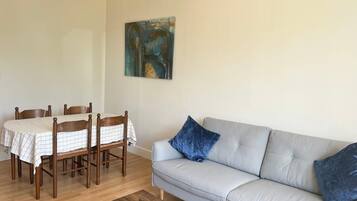 Un salon avec un canapé, une table à manger et des chaises, et un tableau accroché au mur.