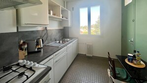 Una cocina compacta con estufa a gas, un lavamanos y un ventanal que proporciona luz natural.