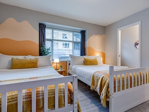 Two single beds with matching bedding and throw blankets, a bedside table, and a potted plant.
