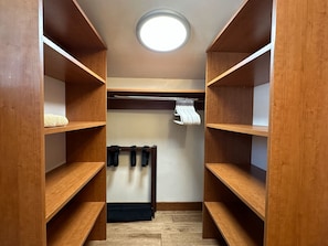 A walk-in closet with wooden shelving, a hanging rod, and a circular ceiling light.