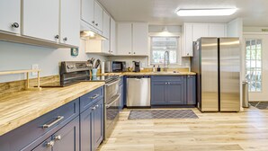 Una cocina moderna con electrodomésticos de acero inoxidable, encimeras de madera y armarios azules.