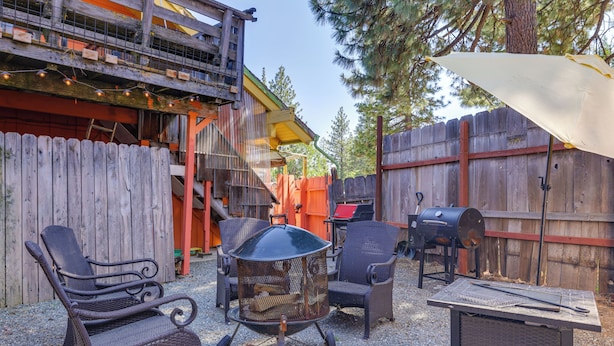 Een terras met rieten stoelen, een metalen vuurkorf en een barbecue.