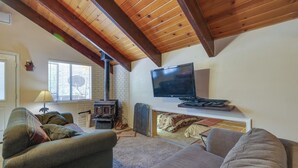 Een gezellige woonkamer met een open haard, een televisie en comfortabele zitplaatsen.