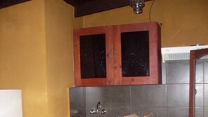 A kitchen with wooden cabinets, a stainless steel sink, and a red countertop.