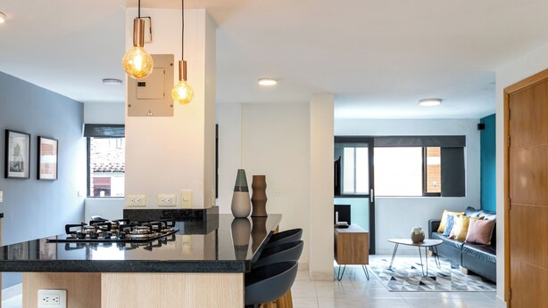 A modern kitchen with a central island, bar stools, pendant lighting, and a view to the living area. - Stylish 2BR unit in the Best Scene in Medellin next to Poblado Park (Medellín)