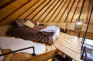Cozy A-frame room with a bed, wooden table, and chair.