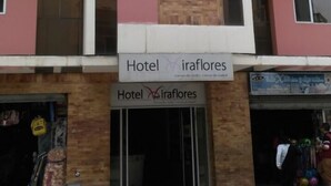 A multi-story hotel with a pink and beige facade, featuring a prominent vertical brick column. The entrance has a sign reading "Hotel Miraflores." - Hotel Residencial Miraflores (Loja)