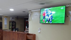 A reception area with a television mounted on the wall displaying a sports event. - Hotel Residencial Miraflores (Loja)