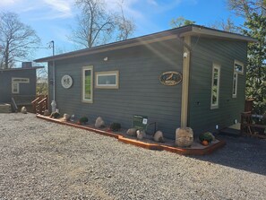 A small, single-story building with a wooden deck, a mailbox, and a sign indicating 'Happy Bottom North.'