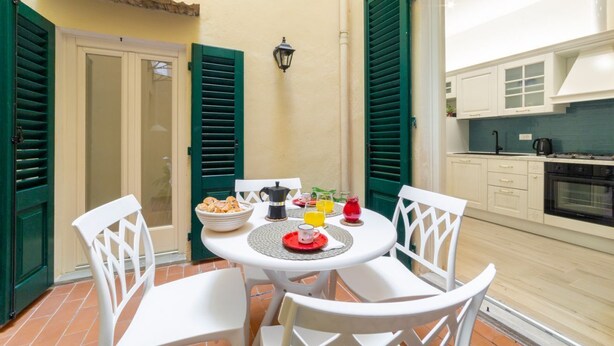 A dining area with a round table, white chairs, and a breakfast setting.