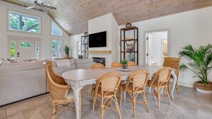 A spacious living area with a large dining table, wicker chairs, a sofa, and a ceiling fan. - Oleander Cottage! Pet Friendly, Heated Pool, Private Escape, 2 Minutes to Beaches and Restaurants (Saint Simons Island)