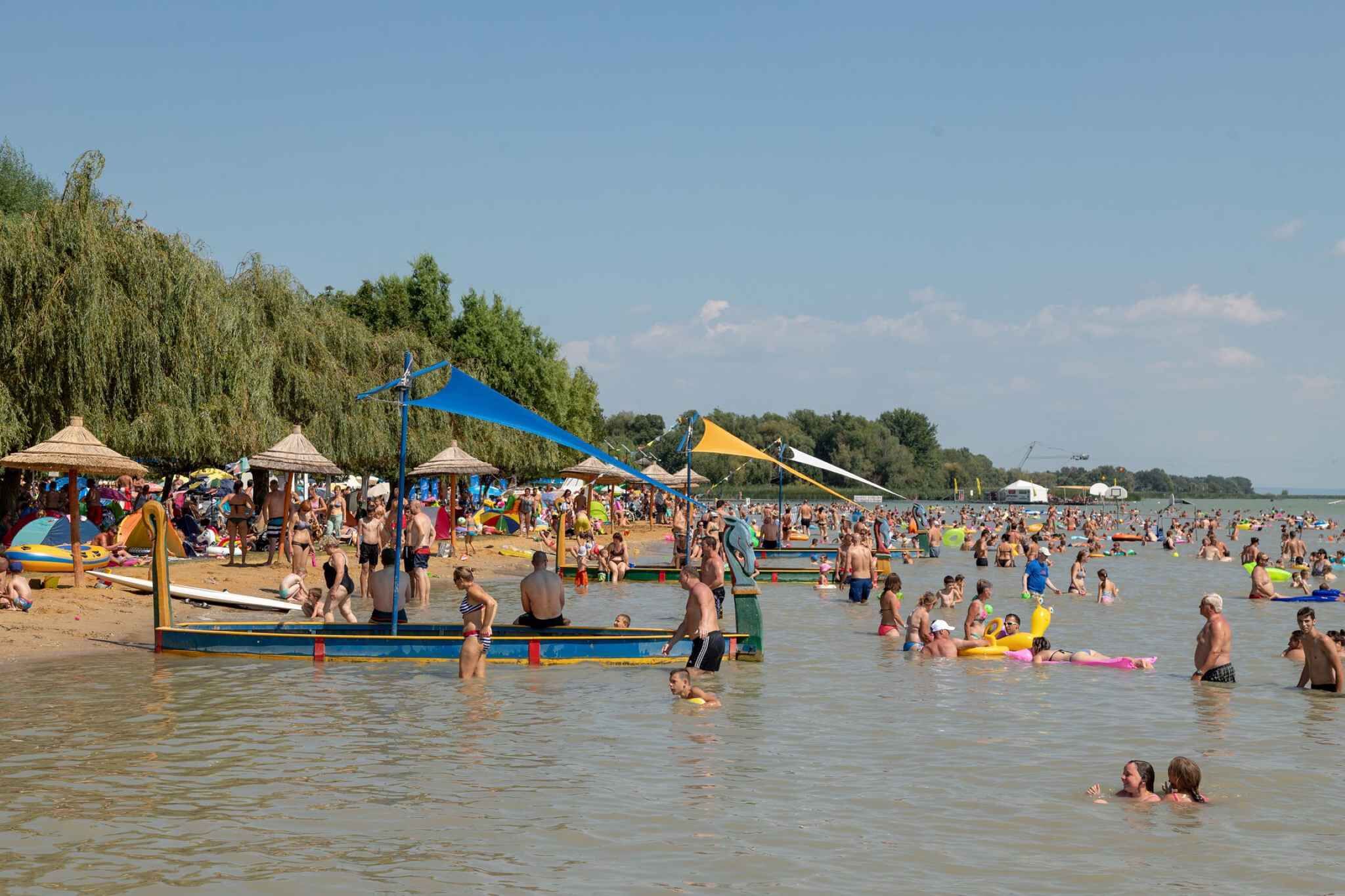 A crowded beach with people swimming and sunbathing.