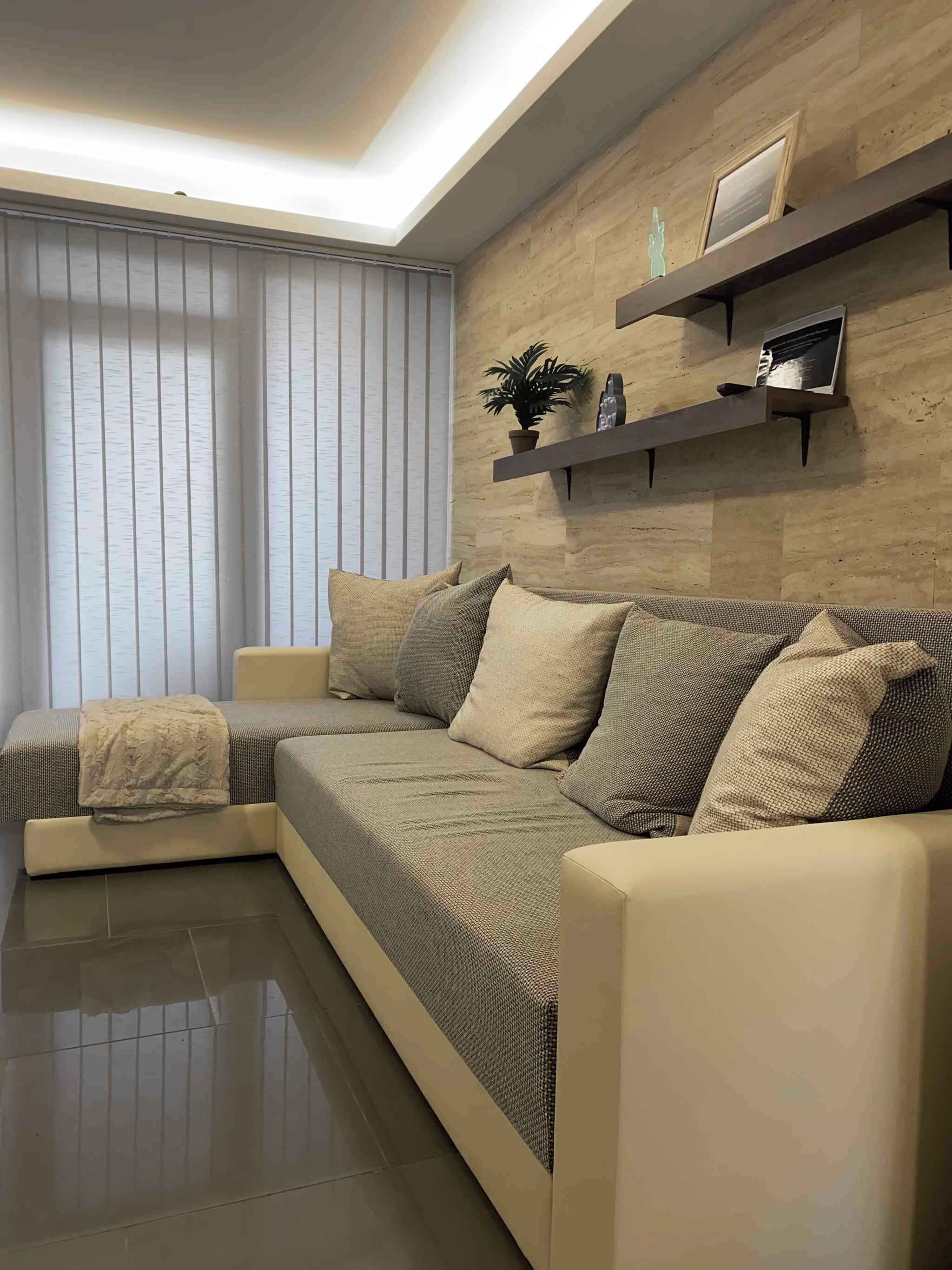 Una sala de estar moderna con un sofá seccional, una mesita auxiliar y un estante empotrado con objetos decorativos.