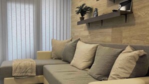 Ein modernes Wohnzimmer mit einem Ecksofa, einem kleinen Beistelltisch und einer eingebauten Regalanlage mit Dekoration.