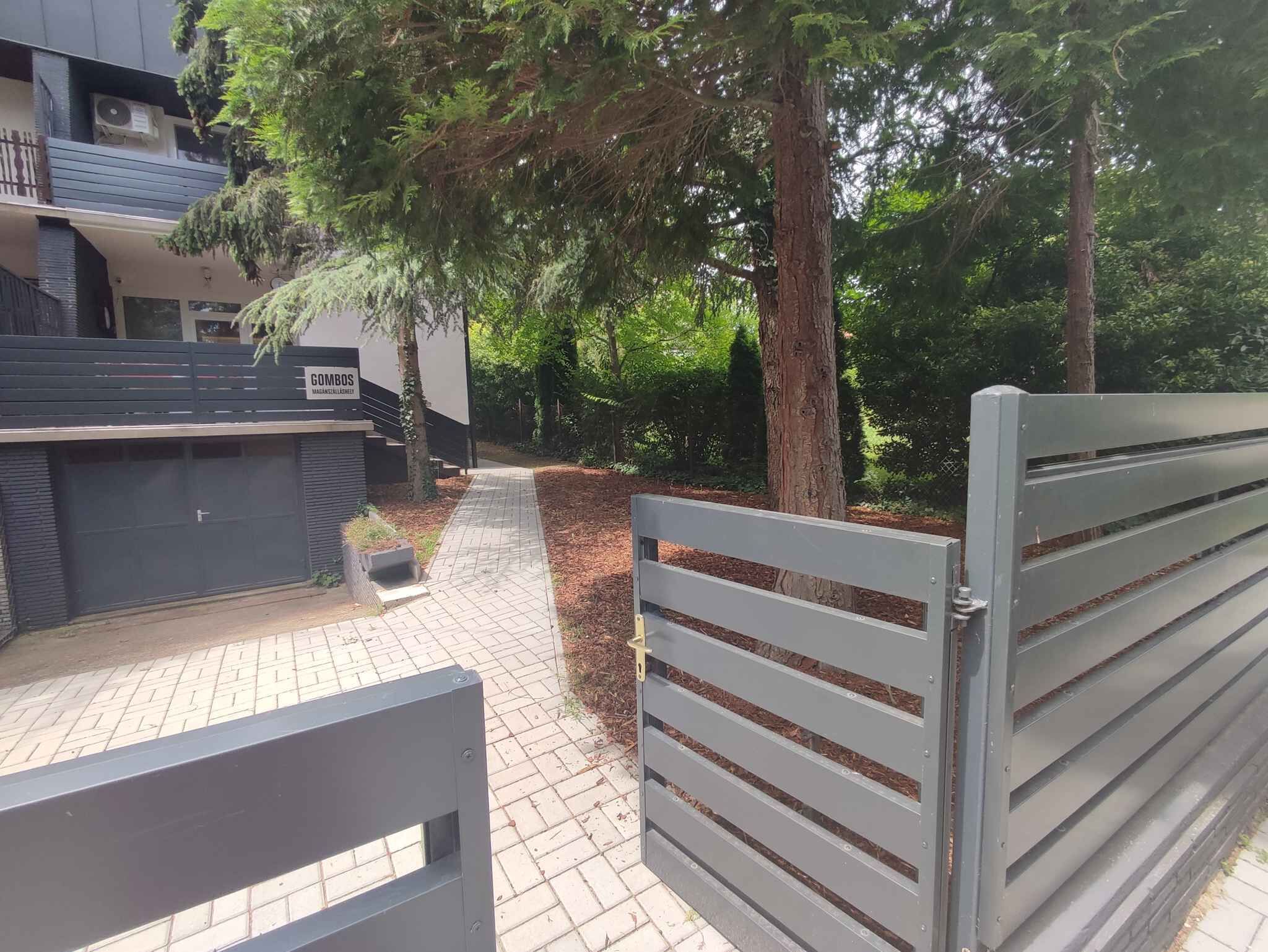 A gated entrance to a building with a paved pathway leading to a bench area.