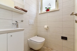 Un baño moderno con inodoro, lavamanos y perchero para toallas.