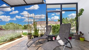 A terrace with two lounge chairs, potted plants, and a view of a building with scaffolding. - Apartment 2284/76144 (Istria - Medulin), 350m from the beach (Medulin)