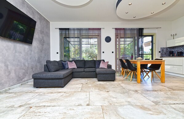 A modern living room with a sectional sofa, dining table, and chairs.