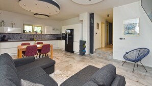 A modern kitchen with white cabinets, a black refrigerator, and a dining area with a wooden table and red chairs. - Apartment 2284/76144 (Istria - Medulin), 350m from the beach (Medulin)