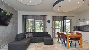 A modern living room with a sectional sofa, dining table with chairs, and a kitchen area. - Apartment 2284/76144 (Istria - Medulin), 350m from the beach (Medulin)