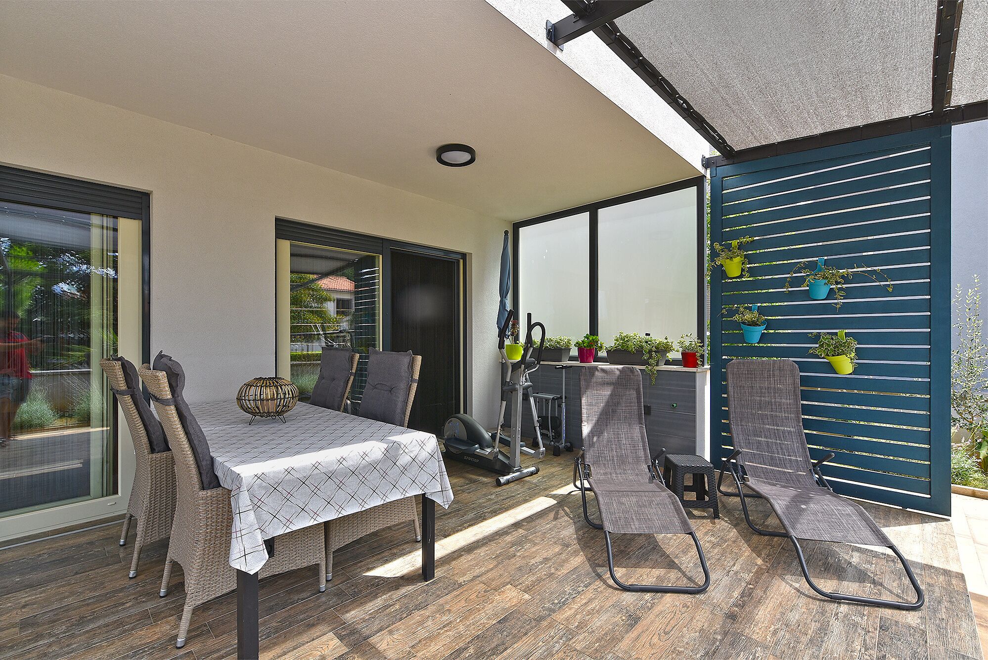 An outdoor patio with a dining table, chairs, and a treadmill.