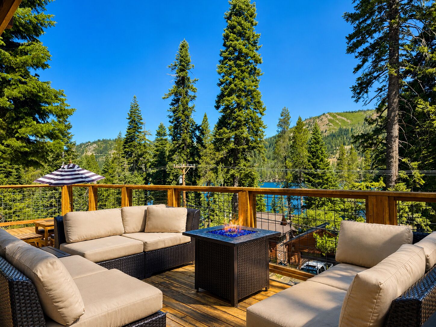 A deck with outdoor furniture, a fire pit, and a view of a forested mountain area.