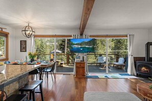 A modern kitchen with a large island, a dining area with chairs, a TV, and a fireplace. - Pet-Friendly Lake View Retreat | 2 Queens, Hot Tub, Game Room | Near Donner Lake (Truckee)