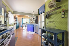 A kitchen with a stainless steel refrigerator, a blue cabinet, and a hanging pot rack.