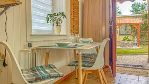Et spiseområde med et bord og stole, en potteplante og udsigt til haven.