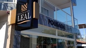 En byggnad med en skylt där det står ”POUSADA LEAL” och en entré med glasfasad.